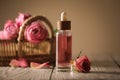 Bottle of essential rose oil and flowers on white wooden table against beige background, space for text Royalty Free Stock Photo