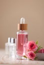Bottle of essential rose oil and flowers on white wooden table against beige background Royalty Free Stock Photo