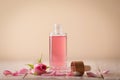 Bottle of essential rose oil and flowers on white wooden table against beige background Royalty Free Stock Photo