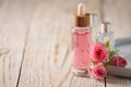 Bottle of essential rose oil and flowers on white wooden table, space for text Royalty Free Stock Photo