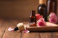 Bottle of essential rose oil and flowers on wooden table, space for text Royalty Free Stock Photo