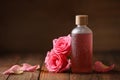 Bottle of essential rose oil and flowers on wooden table, space for text Royalty Free Stock Photo