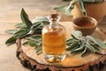 Bottle of essential sage oil, twigs and bowl on wooden table Royalty Free Stock Photo