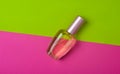 A bottle of female perfume on a green pink background. Top view