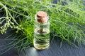 A bottle of fennel essential oil with fresh fennel tops