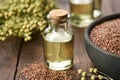 Bottle of linseed oil and bowl of whole flax seeds. Bundle of linen flax plants on table