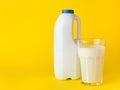 Bottle with fresh milk with handle and glass of milk on yellow background. Mock up for brand template. Royalty Free Stock Photo