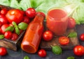 Bottle of fresh organic tomato juice with fresh raw tomatoes in box on stone kitchen background on black Royalty Free Stock Photo