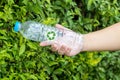 Bottle of fresh water on green tree wall. Hand holding plastic water bottle in concept recycle save the earth and environment