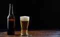 A bottle and a glass of beer on a wooden table, dark background Royalty Free Stock Photo