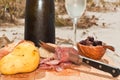 Bottle. and glass of champagne, with sliced salami, knife, bowl of black olives, French bread, and yellow pear on wood server Royalty Free Stock Photo