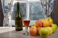 Bottle and glass of cider with apples. near the window, in the rustic house