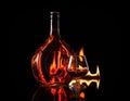 Bottle glass of cognac in fire flame Royalty Free Stock Photo