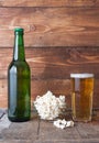 Bottle-glass of cold beer with popcorn on wooden table