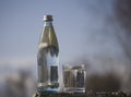 Bottle and glass with cold fresh water against the sky Royalty Free Stock Photo
