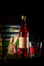 Bottle and glass with craft cranberry alchol drink on background with books