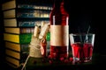 Bottle and glass with craft cranberry alchol drink on background with books