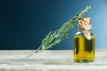 Bottle glass of essential rosemary oil with dry rosemary branch on wooden background