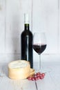 Bottle and glass of red wine, cheese and grapes. Royalty Free Stock Photo