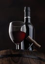 Bottle and glass of red wine with corks and vintage corkscrew on top of wooden barrel on black Royalty Free Stock Photo