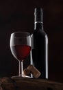 Bottle and glass of red wine with corks and vintage corkscrew on top of wooden barrel on black Royalty Free Stock Photo