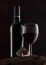 Bottle and glass of red wine with corks and vintage corkscrew on top of wooden barrel on black Royalty Free Stock Photo