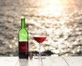 Bottle and glass of red wine on the linen table against the sea or ocean