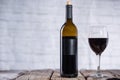 Bottle and glass with red wine on rustic wooden table on white brick background. Concept of alcoholic drink. Photo for advertising Royalty Free Stock Photo