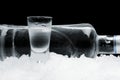 Bottle with glass of vodka lying on ice on black background Royalty Free Stock Photo