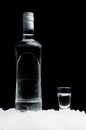 Bottle with glass of vodka standing on ice on black background Royalty Free Stock Photo