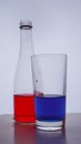 Bottle and glass. In which the red and blue liquids are poured on a white background Royalty Free Stock Photo