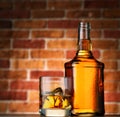 Bottle and glass of whiskey with ice on brick wall background