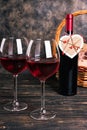 Bottle and glasses of red wine with a gift basket on a wooden table Royalty Free Stock Photo