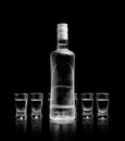 Bottle and glasses of vodka standing isolated on black background