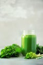 Bottle of green celery smoothie on grey concrete background. Banner with copy space. Square crop. Fresh juice for detox. Vegan,