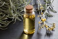 A bottle of helichrysum essential oil with blooming helichrysum