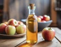 A bottle of homemade apple cider vinegar. Juicy apples and a wooden table in the back.