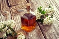 A bottle of homemade hawthorn tincture with blooming hawthorn branches on a table Royalty Free Stock Photo