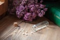 A bottle of homeopathic globules with dried herbs and materia medica