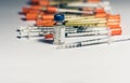 Bottle of insulin for diabetes and injection syringe, healthcare concept with pile of syringes on background