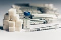 Bottle of insulin for diabetes and injection syringe, healthcare concept with refined loaf sugar cubes pile of syringes on