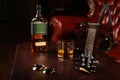 A bottle of Irish whiskey, with a glass, glasses, and a guitar on the table. Place for text or logo Royalty Free Stock Photo