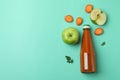 Bottle of juice and ingredients on mint background