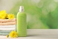 Bottle of laundry detergent, towels and beautiful flowers on white wooden table. Space for text Royalty Free Stock Photo