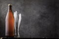 Bottle of light beer and two empty glasses on a wooden table as a human need Royalty Free Stock Photo