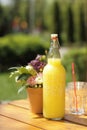 Bottle of limonade on wooden table with small bouquet