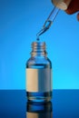 Bottle of liquid on a blue background with reflection. can be used as cosmetic oil Royalty Free Stock Photo