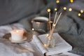 Bottle with liquid home fragrance and wooden bamboo sticks, scentes burn candle and cup of black tea over glow lights at backgroun