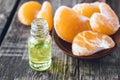 A bottle of mandarin essential oil and slices of ripe yellow mandarin lie on a wooden table Royalty Free Stock Photo