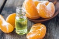 A bottle of mandarin essential oil and slices of ripe yellow mandarin lie on a wooden table Royalty Free Stock Photo